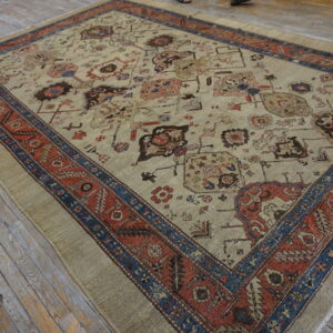 Beige rug featuring geometric motifs, bordered by intricate rust red and navy blue patterns on wood floors.