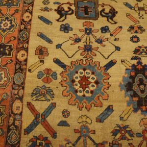 Close-up shows a tan rug with geometric blue and rust motifs and a detailed contrasting orange border.