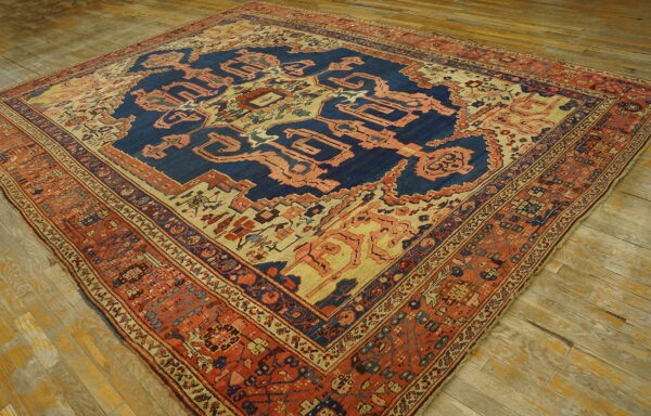 Ornate patterned rug in blue, peach, and terracotta colors laid diagonally on distressed wood flooring.