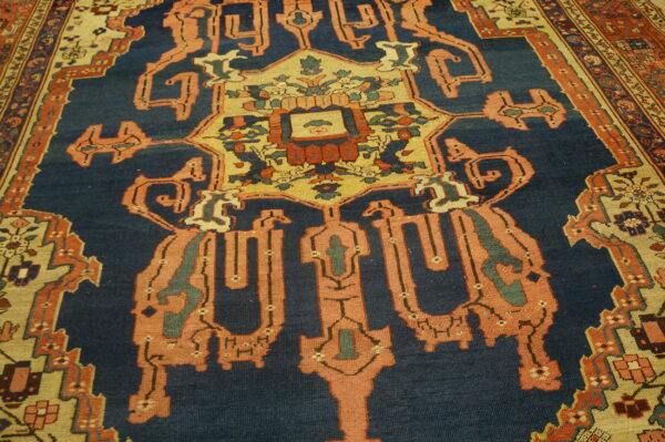 Geometric medallion rug with a navy blue field, coral accents, and detailed cream borders.