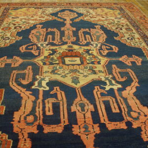 Geometric patterned rug with a faded navy field and coral borders rests on light wood flooring.