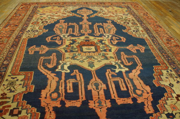 Geometric patterned rug with a faded navy field and coral borders rests on light wood flooring.