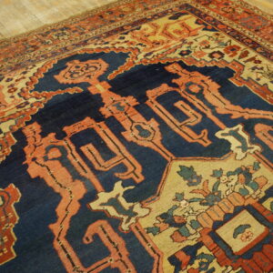 Intricate low-pile rug featuring navy, rust red, and beige geometric patterns on distressed wood flooring.