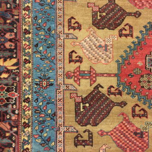 Geometric rug pattern featuring golden tan, deep red, and turquoise designs with stylized animal figures and stepped borders.