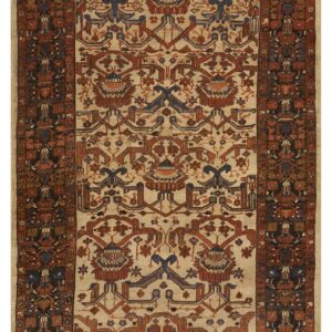 Traditional rug featuring a beige field, stylized rust, and navy blue geometric patterns within a dark ornate border.