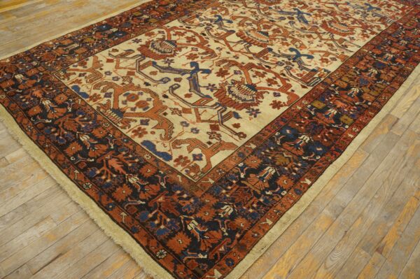 Traditional rug featuring a cream field and rust and blue patterns rests on light wood plank flooring.