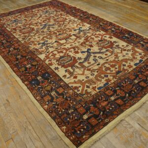 Low-pile rug featuring a cream central field with rust and blue geometric motifs on worn plank wood floor.