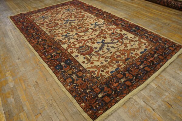 Low-pile rug featuring a cream central field with rust and blue geometric motifs on worn plank wood floor.