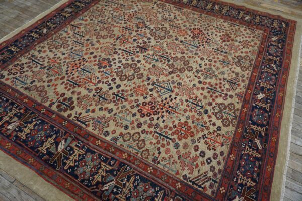 Beige rug with repeating red and blue geometric motifs and wide navy borders on a wood floor.