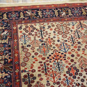 Beige rug field featuring dense red and blue stylized tree motifs framed by a navy geometric animal border.