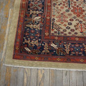 Low-pile patterned rug in cream, red, and navy blue on distressed, gray and yellow wood planks.