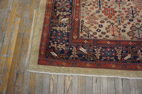 Low-pile patterned rug in cream, red, and navy blue on distressed, gray and yellow wood planks.