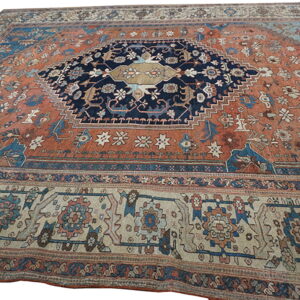 Rust-colored rug with a navy central medallion, featuring intricate blue and beige traditional patterns.