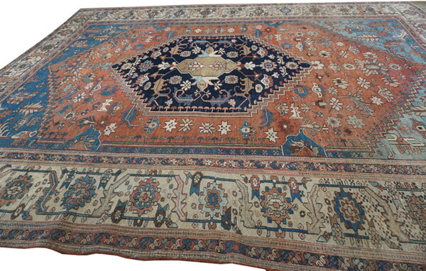 Rust-colored rug with a navy central medallion, featuring intricate blue and beige traditional patterns.