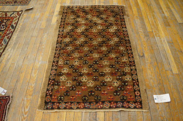 Geometric brown runner rug featuring rust and cream motifs displayed on worn yellow wooden floorboards.