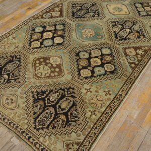 Large geometric rug in teal, brown, and black, laid on distressed plank hardwood flooring.