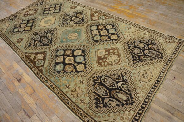 Faded teal, brown, and black geometric rug with large repeating medallions on weathered wood planks.
