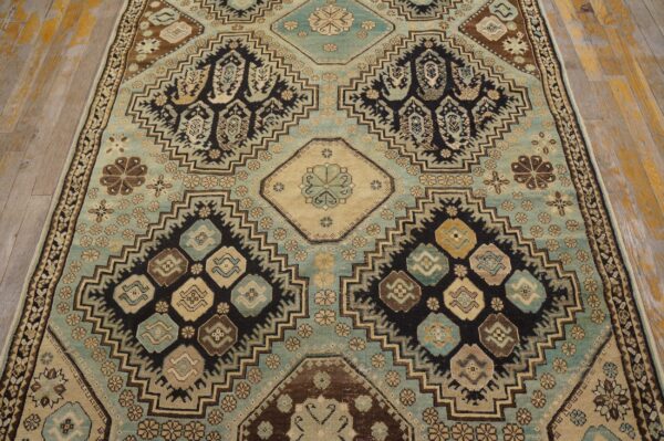 Traditional rug with stepped medallions in dusty blue, black, and brown rests on distressed wood floors.