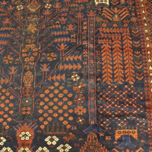 Detail view of a rug showing dense geometric patterns in dark blue and reddish-orange tones.