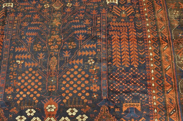 Detail view of a rug showing dense geometric patterns in dark blue and reddish-orange tones.