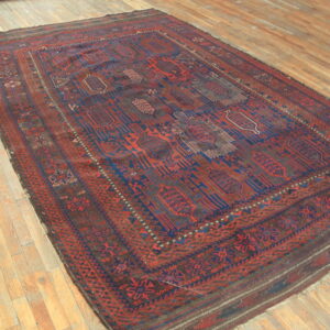 Deep red and blue geometric patterned rug angled on natural wood plank flooring.