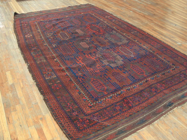 Deep red and blue geometric patterned rug angled on natural wood plank flooring.