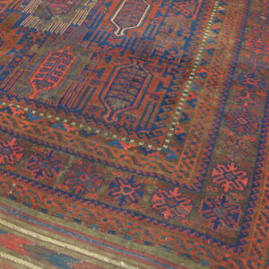 Geometric rug in deep red, navy blue, and brown covering light natural wood floor.
