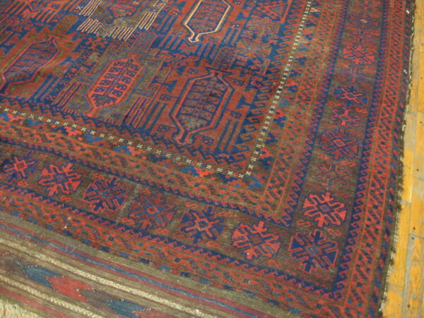 Geometric rug in deep red, navy blue, and brown covering light natural wood floor.