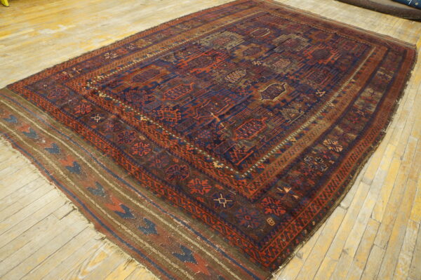 A dark blue and rust geometric rug with flatweave kilim ends lies on light yellow distressed wood floors.