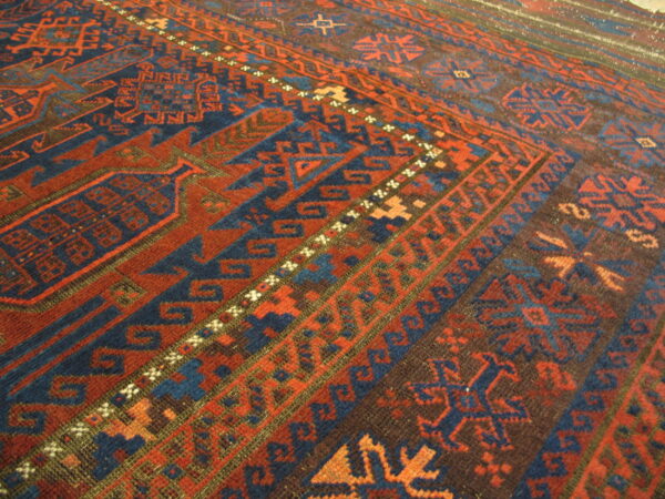 Geometric patterned rug detail showing colors of terracotta red, deep indigo, and dark brown.