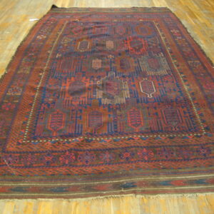 Low-pile red and navy rug with repeating geometric medallions and multiple borders on a wood floor.