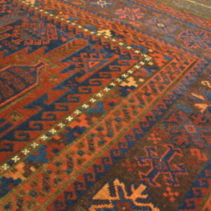 Geometric rug detail shows repeating borders with angular motifs in red, blue, and dark brown.