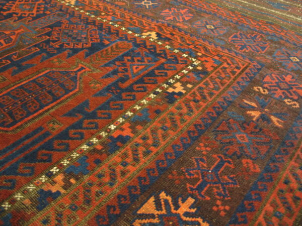 Geometric rug detail shows repeating borders with angular motifs in red, blue, and dark brown.