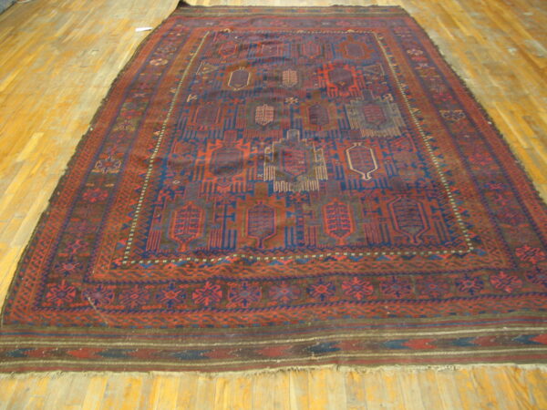 Deep red and navy geometric rug with detailed borders lies flat on polished light hardwood flooring.
