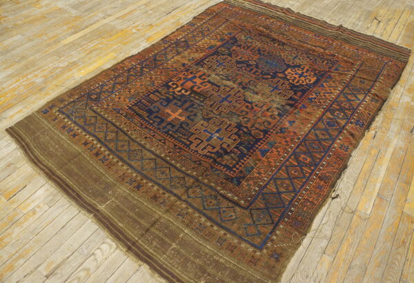 Distressed geometric rug in rust, navy, and brown with flatwoven ends on light plank flooring.
