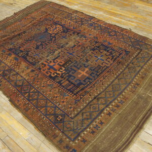 Geometric blue, rust, and brown rug with tribal patterns laid diagonally on aged wooden planks.