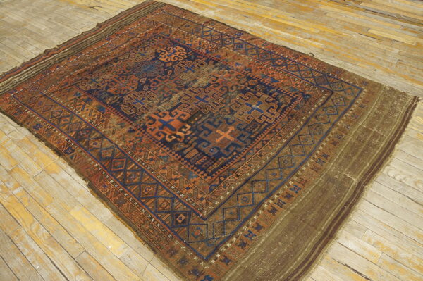 Geometric blue, rust, and brown rug with tribal patterns laid diagonally on aged wooden planks.