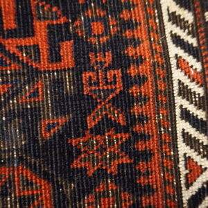 Textured detail shot showing a navy and rust geometric pattern, bordered by cream zigzags and blue selvage.