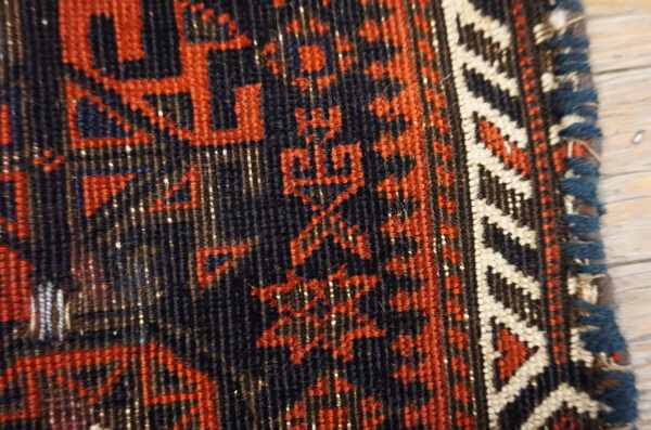 Textured detail shot showing a navy and rust geometric pattern, bordered by cream zigzags and blue selvage.