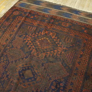 Low-pile tribal rug with dark blue and terracotta geometric designs on distressed hardwood.