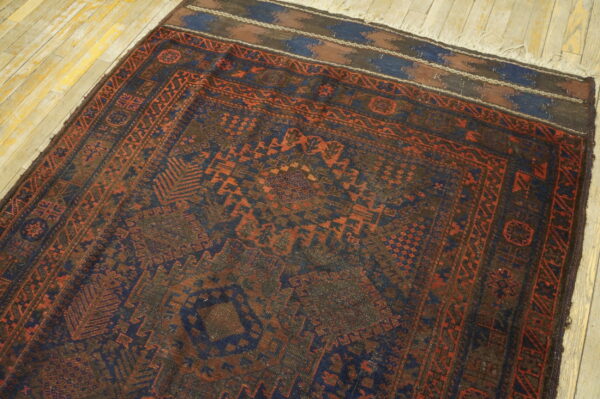 Low-pile tribal rug with dark blue and terracotta geometric designs on distressed hardwood.
