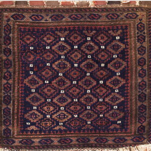 Geometric rug in navy, reddish-brown, and dark brown, featuring repeating diamond motifs and visible fringe.