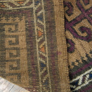 Brown, purple, and cream geometric rug detail shows mixed flat and high-pile textures on wood flooring.