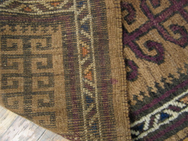 Brown, purple, and cream geometric rug detail shows mixed flat and high-pile textures on wood flooring.