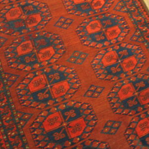 Rust and navy blue rug featuring large repeating octagon motifs on light wood flooring.