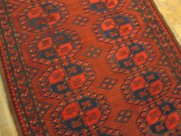 Rust and navy blue rug featuring large repeating octagon motifs on light wood flooring.
