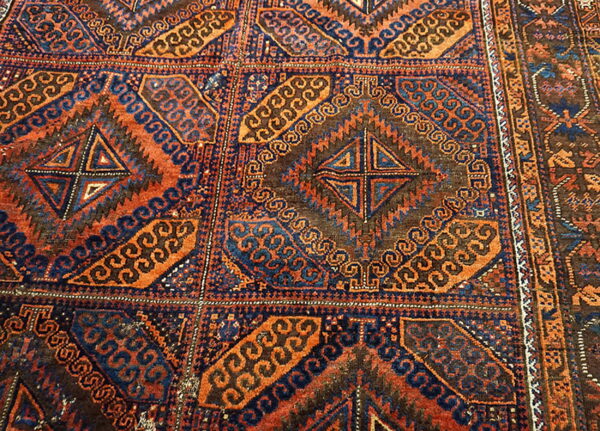 Geometric rug pattern featuring repeating squares with internal crosses, colored in deep orange, navy, and brown.