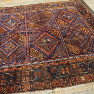 Low pile rug featuring a dark blue and terracotta geometric pattern on light wooden planks.
