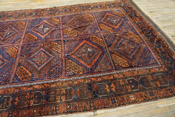 Low pile rug featuring a dark blue and terracotta geometric pattern on light wooden planks.
