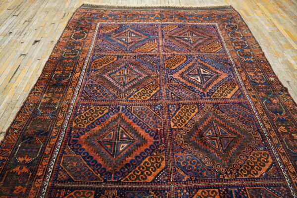 A tribal-style rug featuring deep blue, orange, and brown geometric patterns is laid on rustic wood planks.